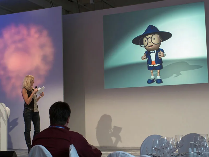 Digital AutoScout24 mascot Scouty on an event stage next to a presenter